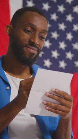 Vertical-Video-Shot-Of-Man-With-Ballot-Paper-In-American-Election-Deciding-How-To-Cast-His-Vote